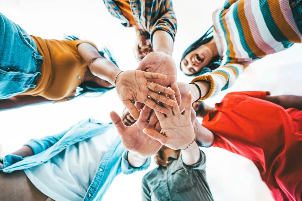 Community of millennial people stacking hands together